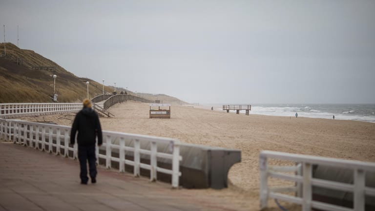 Ein Spaziergänger blickt auf das Meer: An diesem Donnerstag ist nur wenig los am Strand von Westerland.