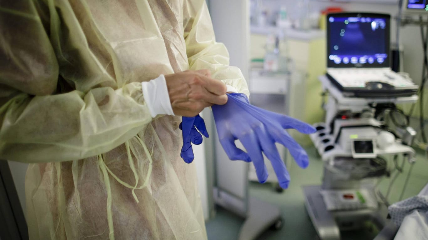 Eine Ärztin zieht sich blaue Handschuhe an (Symbolbild): Der Bund zahlt den Kliniken 2,5 Milliarden Euro.