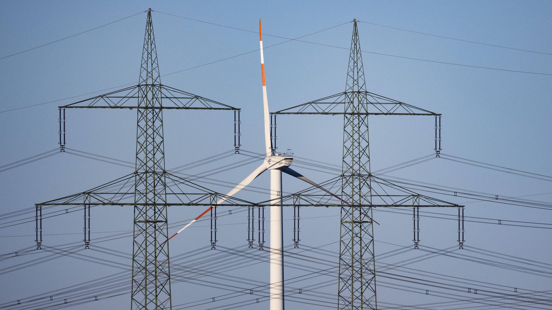 Ein Windrad und zwei Hochspannungsmasten (Symbolbild): Viele Energiediscounter geraten wegen der hohen Strom- und Gaspreise in Schwierigkeiten.