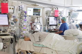 Ein Pfleger untersucht einen Patienten auf einer Covid-19-Intensivstation (Archivbild): München verzeichnet durch Corona einen Engpass beim Klinikpersonal.