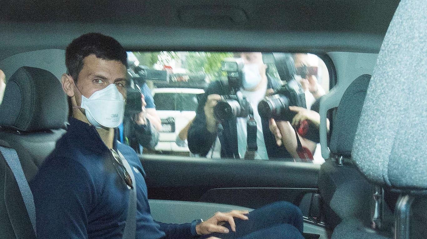 Novak Djokovic sitzt in einem Auto auf dem Weg zu seinen Anwälten: Er wird von Polizeibeamten bewacht.