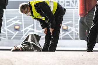 Der Busfahrer des FC Augsburg liegt am Boden. Weitere Ordner kümmern sich um ihn.