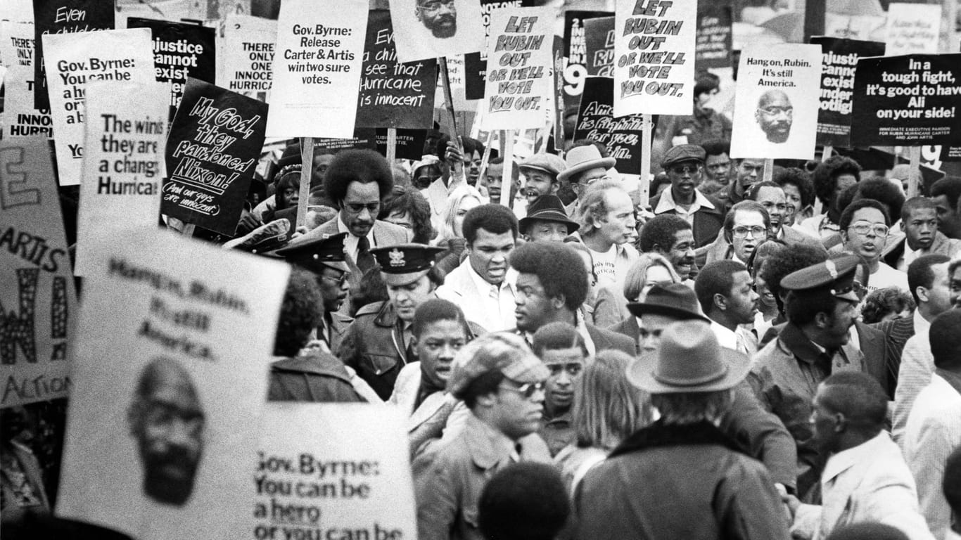 Oktober 1975: Ali (M.) auf einer Demonstration für die Freilassung des unter zweifelhaften Umständen inhaftierten Boxers Hurricane Carter und dessen Freundes John Artis.
