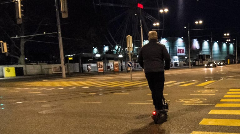 Ein Mann fährt nachts mit einem E-Scooter (Symbolbild): Politiker fordern strengere Regeln für den Gebrauch der Roller.