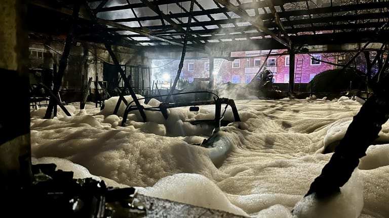 Brand in Halle: Der Boden einer ausgebrannten Lagerhalle ist mit Löschschaum bedeckt.