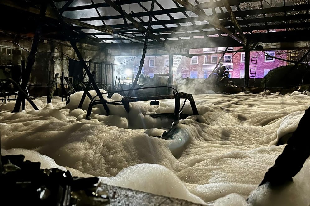 Brand in Halle: Der Boden einer ausgebrannten Lagerhalle ist mit Löschschaum bedeckt.