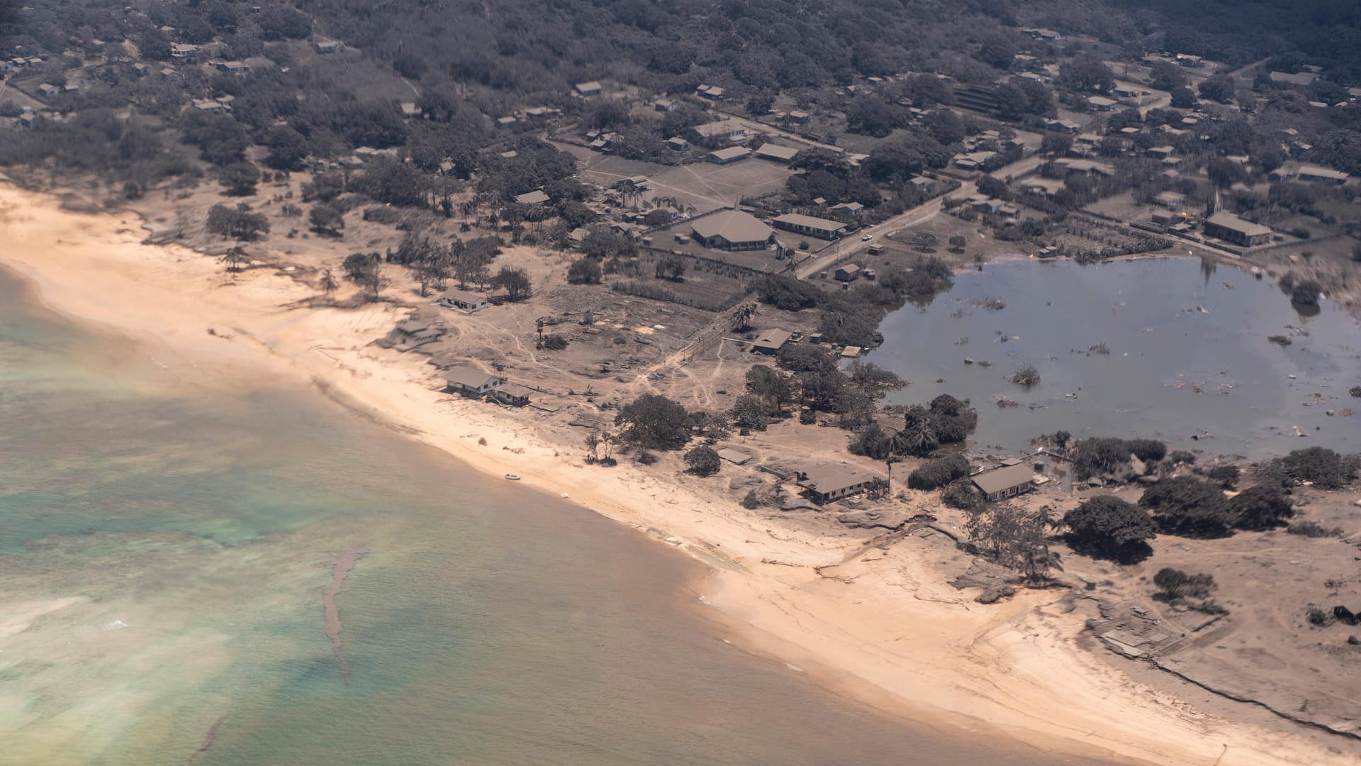 Inselabschnitt: Ein von der New Zealand Defence Force (NZDF) zur Verfügung gestelltes Bild zeigt den Blick aus einem P-3K2 Orion-Flugzeug, das über mit Asche bedeckte Häuser und Vegetation fliegt.