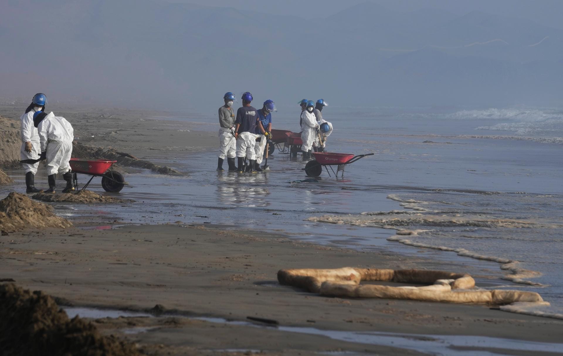 Peru, Callao: Arbeiter beseitigen einen Ölteppich am Cavero Strand in Ventanilla. Ungewöhnlich hohe Wellen, die die Behörden auf den Ausbruch des unterseeischen Vulkans in Tonga zurückführen, verursachten einen Ölunfall an der peruanischen Pazifikküste, während ein Schiff am Sonntag Öl in die Raffinerie La Pampilla verlud.
