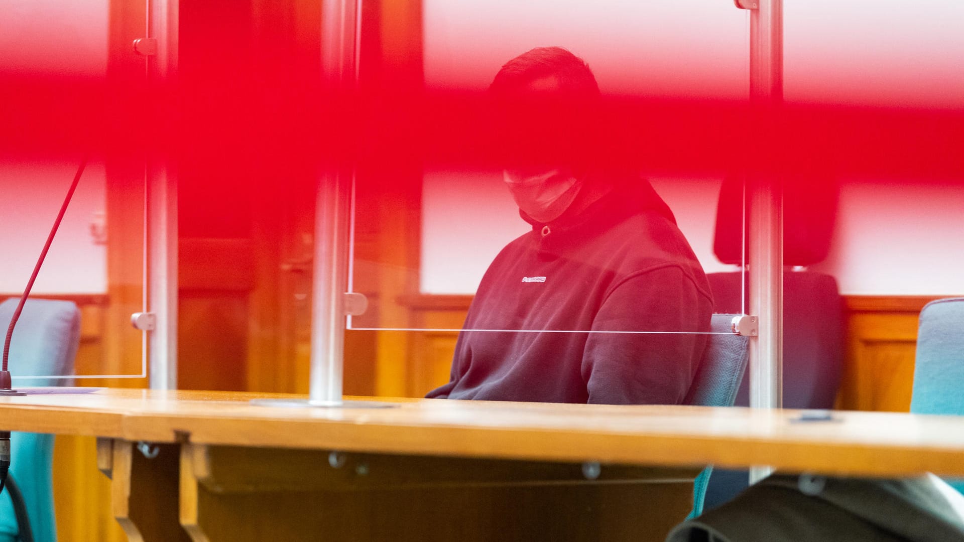 Der Angeklagte sitzt vor Prozessbeginn hinter einem Absperrband im Saal des Landgerichts Lüneburg. Die drei Leichen der Mutter und ihrer Kinder wurden in einem Wald gefunden. Der Angeklagte sitzt vor Prozessbeginn hinter einem Absperrband im Saal des Landgerichts Lüneburg. Die drei Leichen der Mutter und ihrer Kinder wurden in einem Wald gefunden.