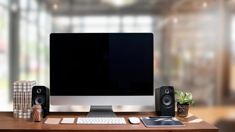 Ein PC steht mit Tastatur, Maus und Lautsprechern auf einem Tisch.
