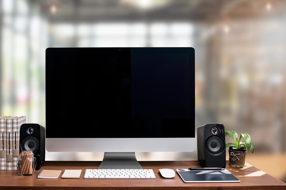 Ein PC steht mit Tastatur, Maus und Lautsprechern auf einem Tisch.