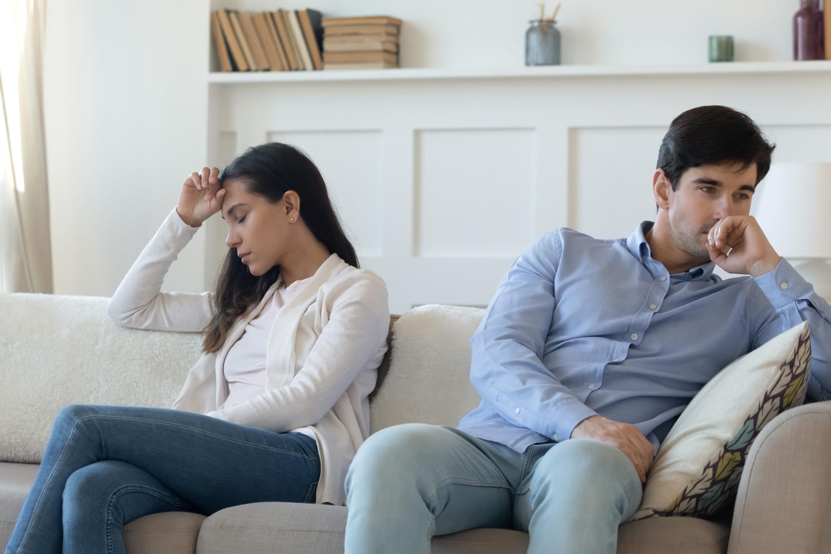 Paar sitzt distanziert voneinander auf dem Sofa:Über Blasenschwäche sollte offen mit dem Partner kommuniziert werden. Verschwiegenheit kann zu Distanz führen.