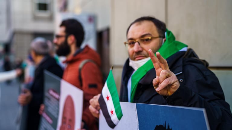 Ein syrischer Aktivist macht vor dem Gerichtsgebäude das Victory-Zeichen: Menschenrechtler begrüßen das Verfahren, das nach dem Weltrechtsprinzip in Deutschland stattfinden kann.
