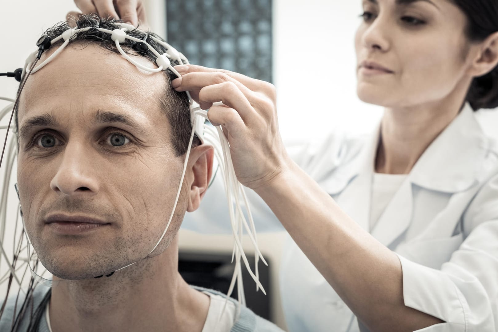 Eine Ärztin legt einem Patienten ein EEG an.