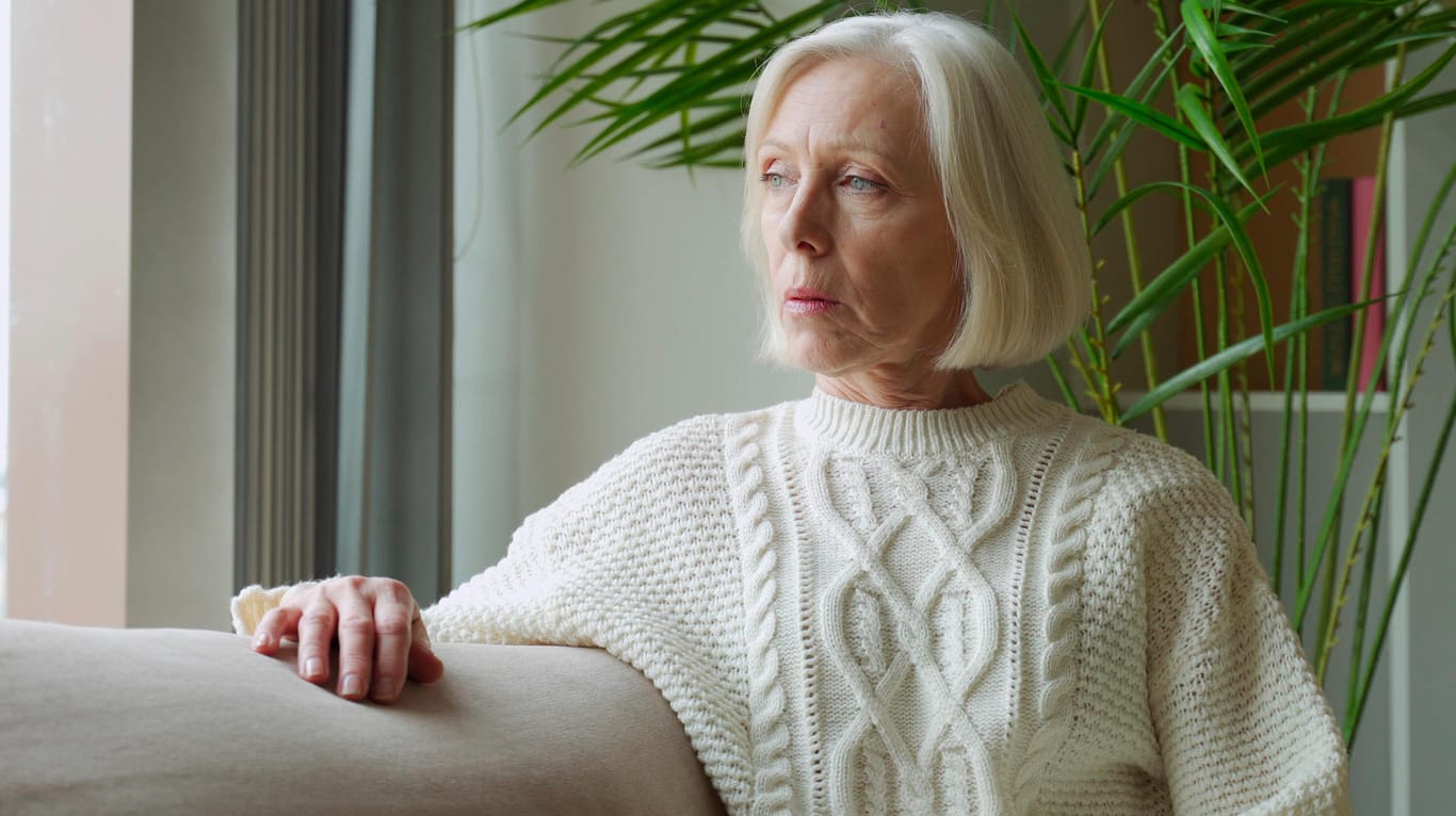 Ältere Frau schaut aus dem Fenster (Symbolbild): Das Umlagesystem der Rente wird 65 Jahre alt.