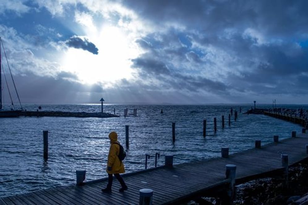 Eine Frau geht an der Ostsee über einen Bootssteg