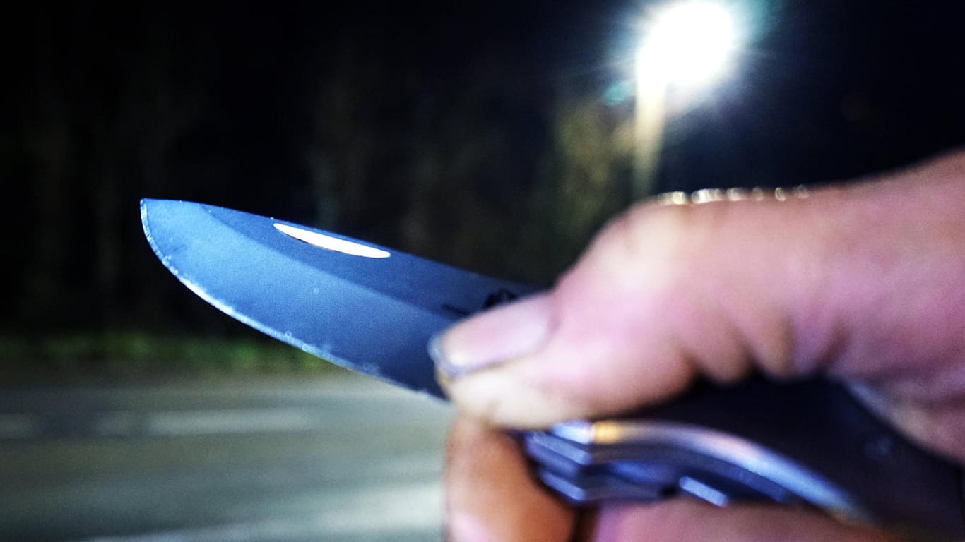 Ein Mann hält ein Messer in der Hand (Symbolbild): Die Täter sollen den Angestellten mit Messern bedroht haben.