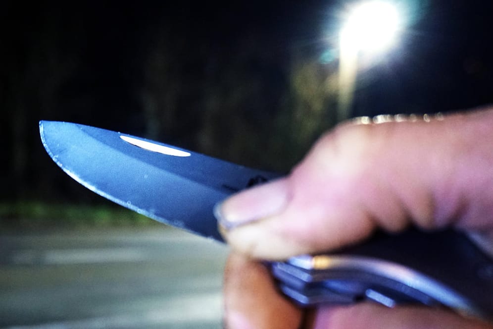Ein Mann hält ein Messer in der Hand (Symbolbild): Die Täter sollen den Angestellten mit Messern bedroht haben.