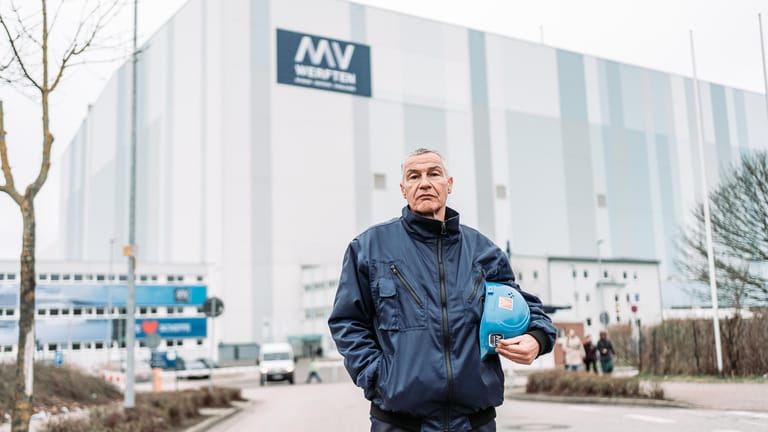 Betriebsrat Folko Manthey vor dem MV-Werften-Standort Wismar: In der Halle hinter ihm liegt die "Global Dream One", aber aktuell ist unklar, ob sie fertiggebaut werden kann.