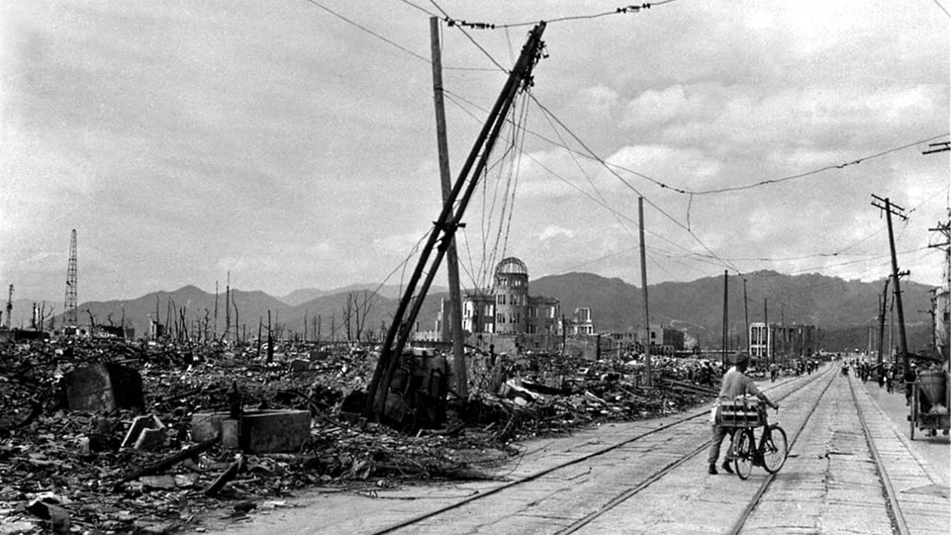 Ein Mann schiebt sein Fahrrad durch die Ruinen von Hiroshima (Symbolfoto): Mehr als 150.000 Menschen starben allein in den ersten Monaten infolge des US-Atombombenabwurfs auf die Stadt. Bis heute kämpfen Überlebende und deren Familien mit den Spätfolgen der Strahlung.