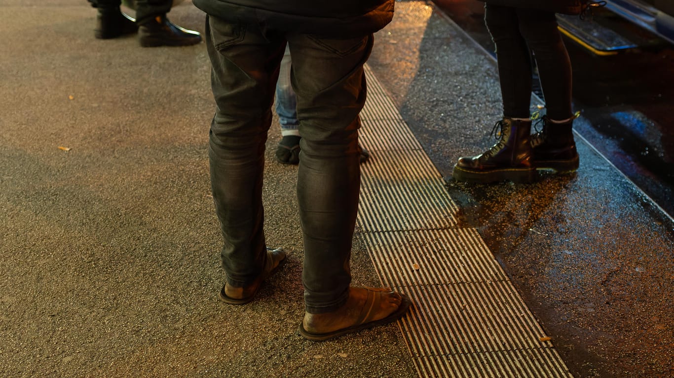 Ein Obdachloser am Ostbahnhof – ohne Socken, nur Badelatschen an den Füßen: Trotz der schneidenden Kälte lacht der Mann viel und wirkt freundlich