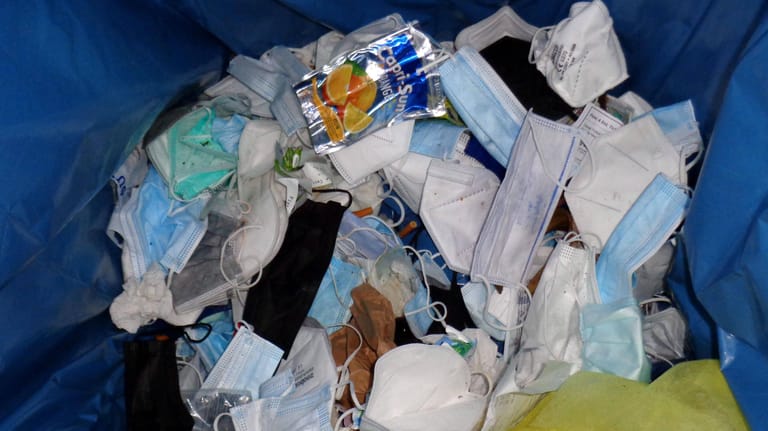 Corona Masken und Getränkeverpackungen in einem Abfallkorb (Symbolbild): Unbekannte haben medizinischen Sondermüll neben einer öffentlichen Mülltonne entsorgt.