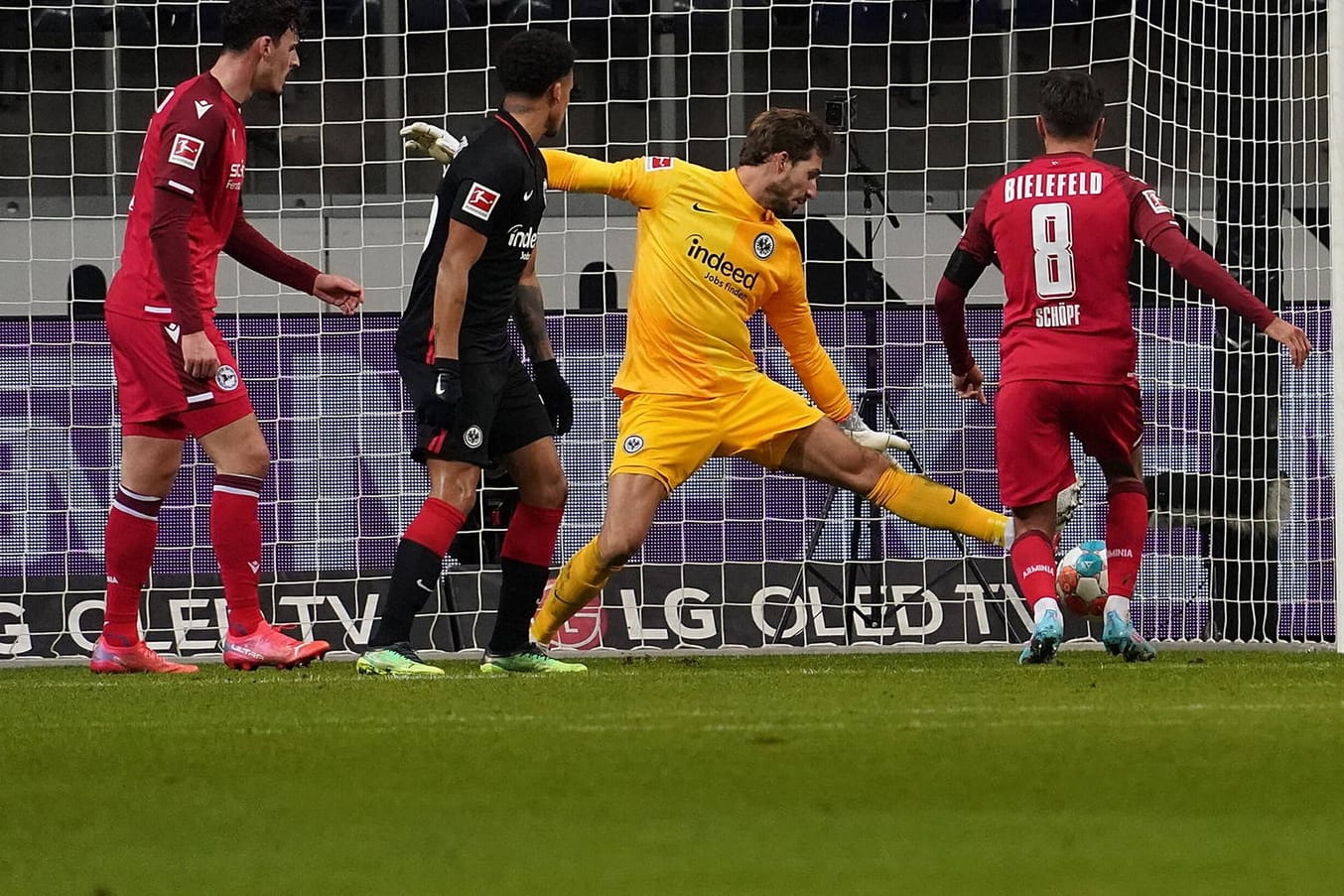 Der Ball von Bielefelds Schöpf fliegt aufs Tor, Frankfurts Torwart Trapp (r.) ist chancenlos.