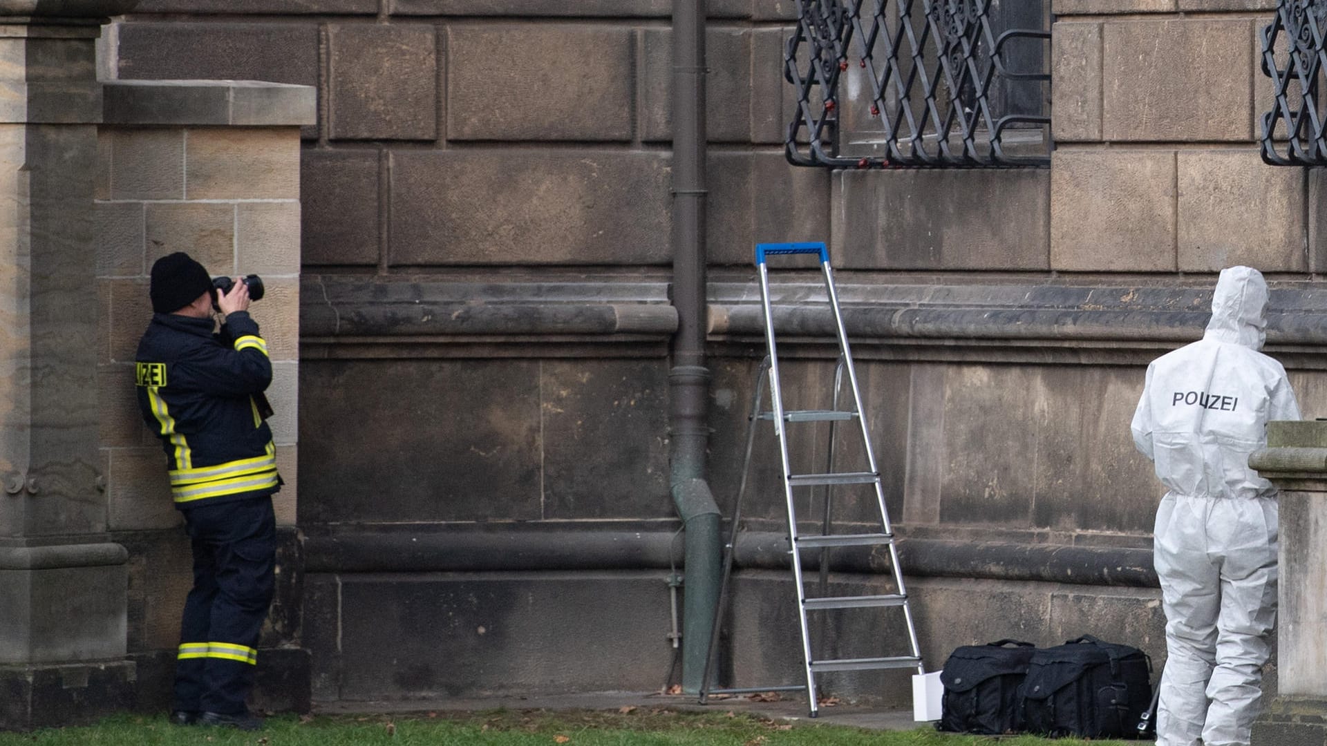 Einsatzkräfte der Polizei stehen im Bärengarten neben einem durchtrennten Gitterfenster des Grünen Gewölbes am Residenzschloss.