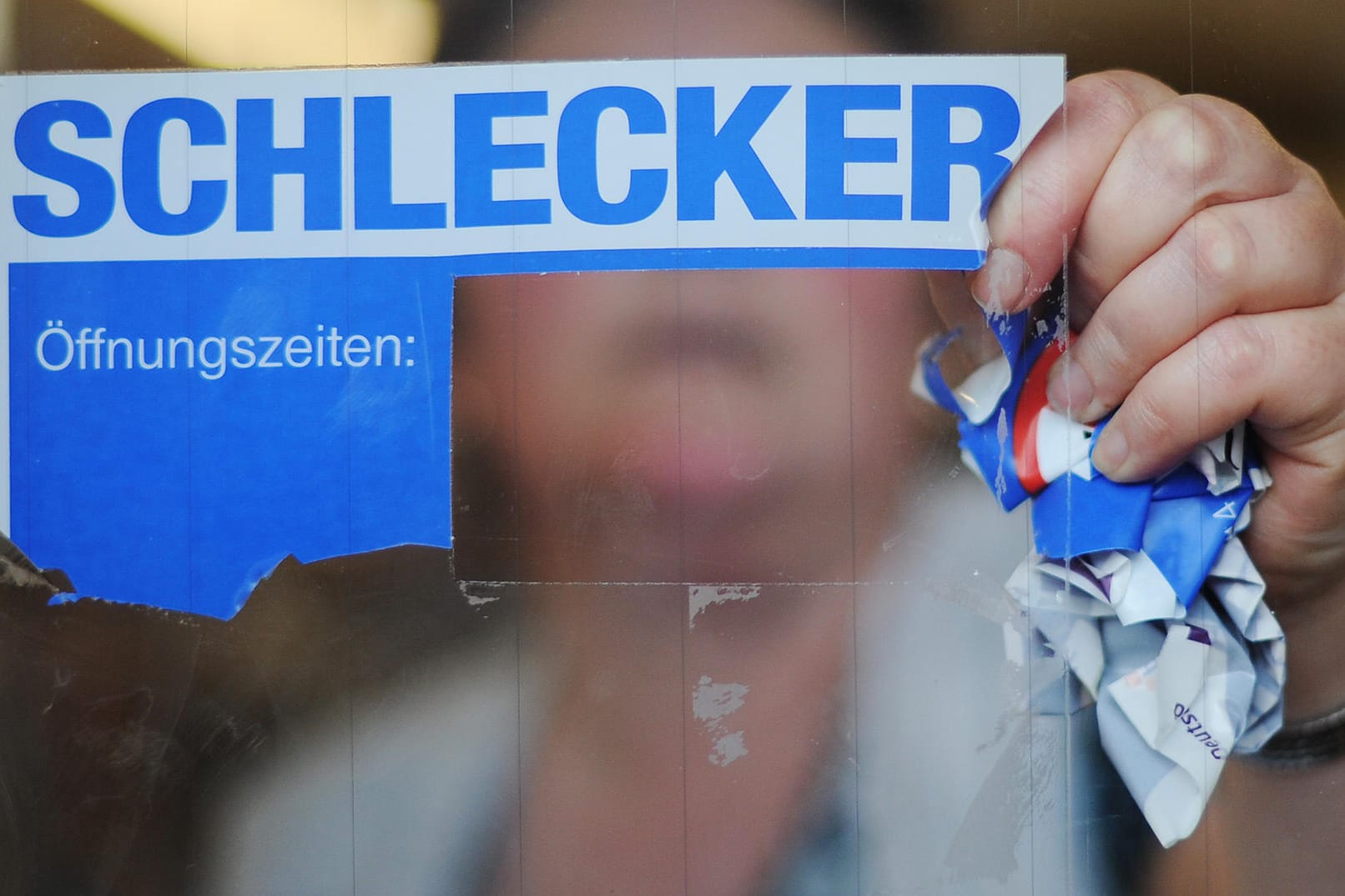 Eine Mitarbeiterin der Drogeriemarktkette Schlecker reißt das Firmenlogo von der Eingangstür einer Filiale (Archivbild): Vor zehn Jahren endete die europaweite Erfolgsgeschichte des Unternehmens.