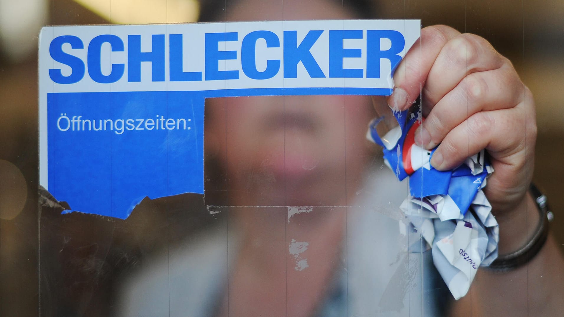 Eine Mitarbeiterin der Drogeriemarktkette Schlecker reißt das Firmenlogo von der Eingangstür einer Filiale (Archivbild): Vor zehn Jahren endete die europaweite Erfolgsgeschichte des Unternehmens.