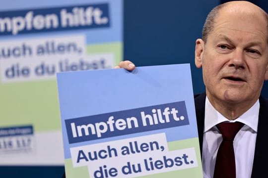 Bundeskanzler Olaf Scholz (SPD) präsentiert ein Plakat für eine neue Impfkampagne.