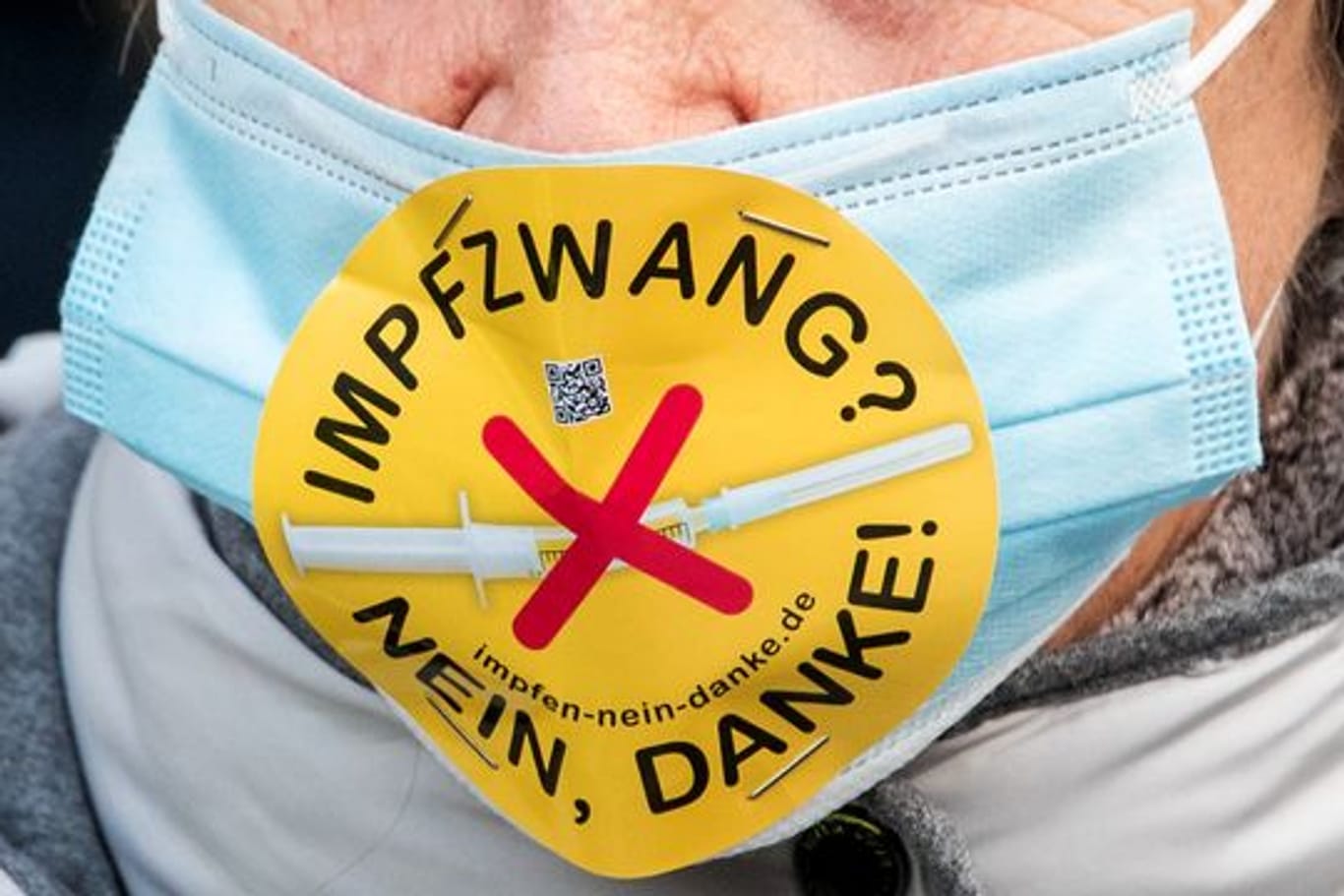 Eine Teilnehmerin einer Demonstration in Hamburg mit einem Mundschutz und der Aufschrift "Impfzwang? Nein, danke!".