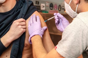Ein junger Mann wird von einem Arzt geimpft (Symbolbild): Die Deutschen stimmen mehrheitlich einer allgemeinen Impflicht zu, so eine Umfrage.