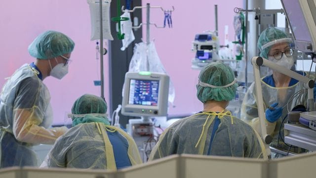 Pflegerinnen und Pfleger sowie eine Ärztin kümmern sich auf der Intensivstation um einen Patienten. Pflegerinnen und Pfleger sowie eine Ärztin kümmern sich auf der Intensivstation um einen Patienten.