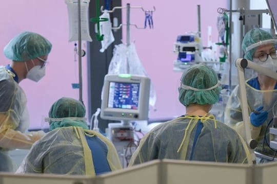 Pflegerinnen und Pfleger sowie eine Ärztin kümmern sich auf der Intensivstation um einen Patienten.