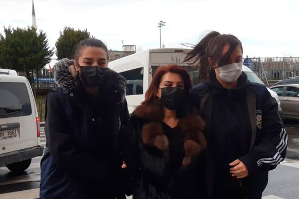 Polizeibeamte eskortieren Sedef Kabas, eine bekannte türkische Journalistin, vor ihrem Auftritt vor Gericht in Istanbul.