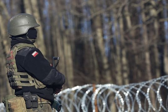 Ein bewaffneter polnischer Soldat bewacht in der Nähe des Ortes Usnarz Gorny die EU-Außengrenze zu Belarus.