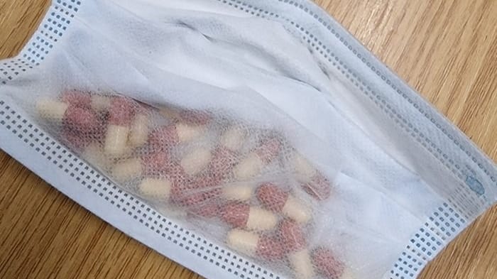 Zwei mutmaßliche Drogendealer haben Pillen in einem Mund-Nasen-Schutz versteckt.