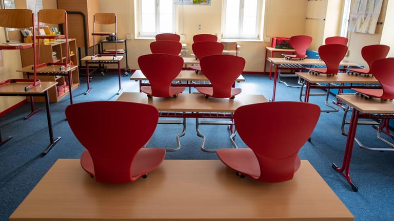 Stühle in einem leeren Grundschulklassenzimmer (Symbolbild): Aufgrund von zahlreichen Corona-Infektionen können in Berlin Eltern ab sofort ihre Kinder aus dem Präsenzunterricht nehmen.