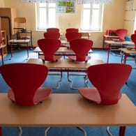 Stühle in einem leeren Grundschulklassenzimmer (Symbolbild): Aufgrund von zahlreichen Corona-Infektionen können in Berlin Eltern ab sofort ihre Kinder aus dem Präsenzunterricht nehmen.