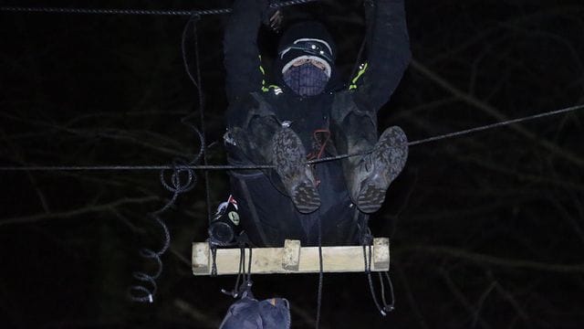 Ein Aktivist sitzt in einem besetzten Waldstück in einem Baum