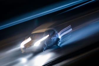 Ein Fahrzeug braust in der Dunkelheit über eine Autobahn.