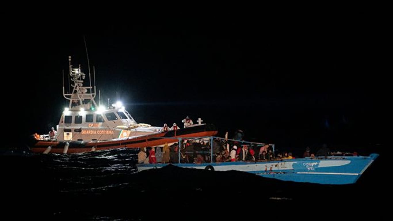 Ein Schiff der Küstenwache fährt zu dem völlig überfüllten Holzboot vor Lampedusa.