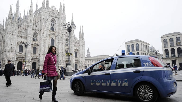 Eine Frau geht auf dem Mailänder Domplatz an einem Polizeiauto vorbei: Die Vorfälle in der Silvesternacht erinnerten an die Silvesternacht 2015/16 in Köln.