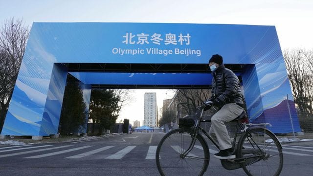 Ein Mann fährt in der Nähe des Athletendorfs in der chinesischen Hauptstadt Peking Fahrrad. Ein Mann fährt in der Nähe des Athletendorfs in der chinesischen Hauptstadt Peking Fahrrad.