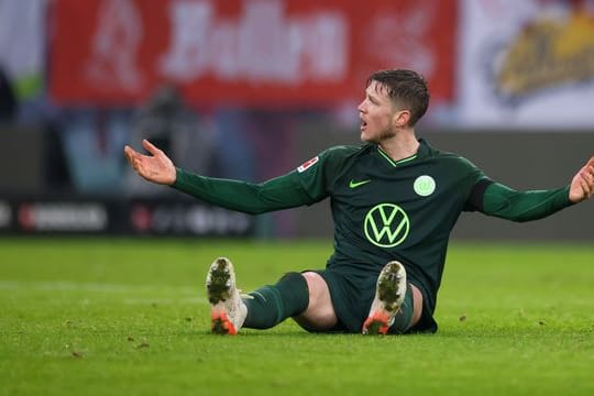 Wolfsburgs Wout Weghorst sitzt auf dem Rasen und gestikuliert.