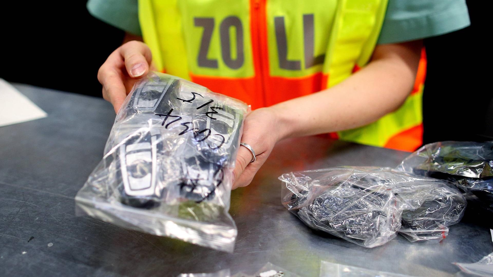 Eine Beamtin des deutschen Zoll eine Plastiktüte voller Mobiltelefone in den Händen (Archivbild): Beamte fanden eine Armbrust in einer Wohnung in Bergkamen.