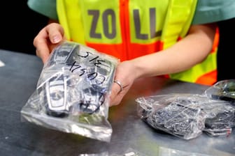Eine Beamtin des deutschen Zoll eine Plastiktüte voller Mobiltelefone in den Händen (Archivbild): Beamte fanden eine Armbrust in einer Wohnung in Bergkamen.