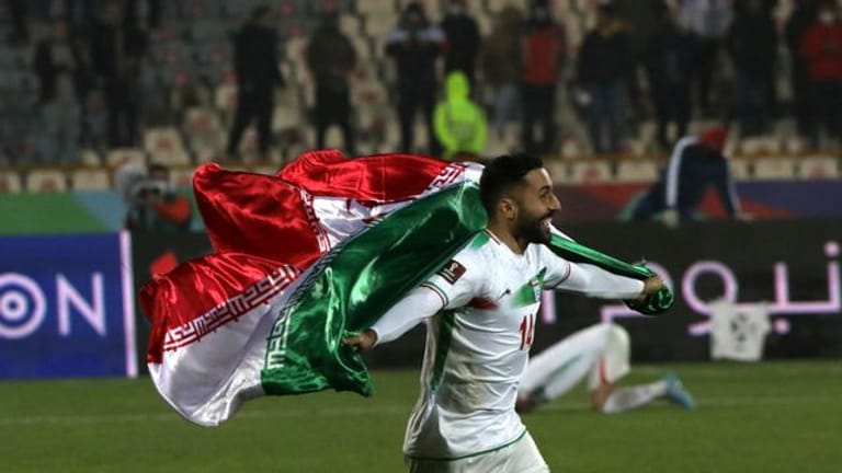 Der Iraner Saman Ghoddoos läuft nach dem Sieg im Azadi Stadion mit einer Fahne über das Spielfeld.