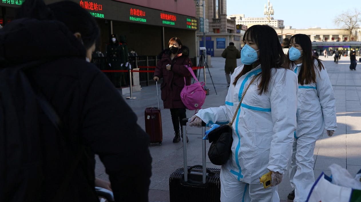 Beijing kurz vor dem Fest: Frauen in Schutzanzügen sind auf dem Weg zum Bahnhof.